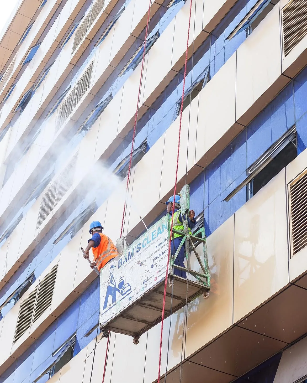Équipe BAM'S CLEAN sur nacelle suspendue, nettoyage haute pression d'une façade à Kinshasa